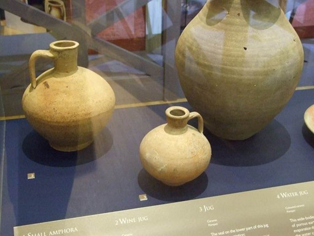I.10.4 Pompeii.  Small ceramic jug (at centre front). SAP 4981. The seal on the lower part of this jug bears the inscription, CN. ATEIUS ARRETINUS, LIBERTUS A ATEIO. It refers to Arretinus, a freedman (former slave) whose pottery business was operated in the town of Ateio around 30-40 BC. Photographed at A Day in Pompeii exhibition at Melbourne Museum.  September 2009.