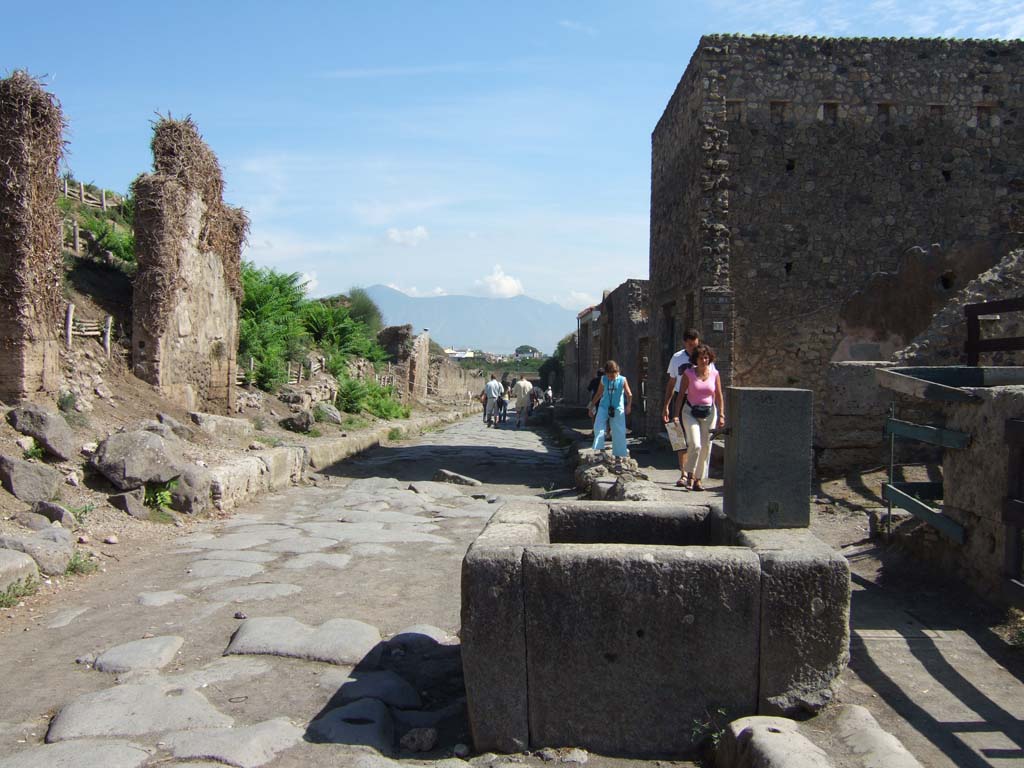 III.6, and III.7.1 Pompeii, on left. September 2005. Via dell’Abbondanza at II.3.5, on right behind fountain.