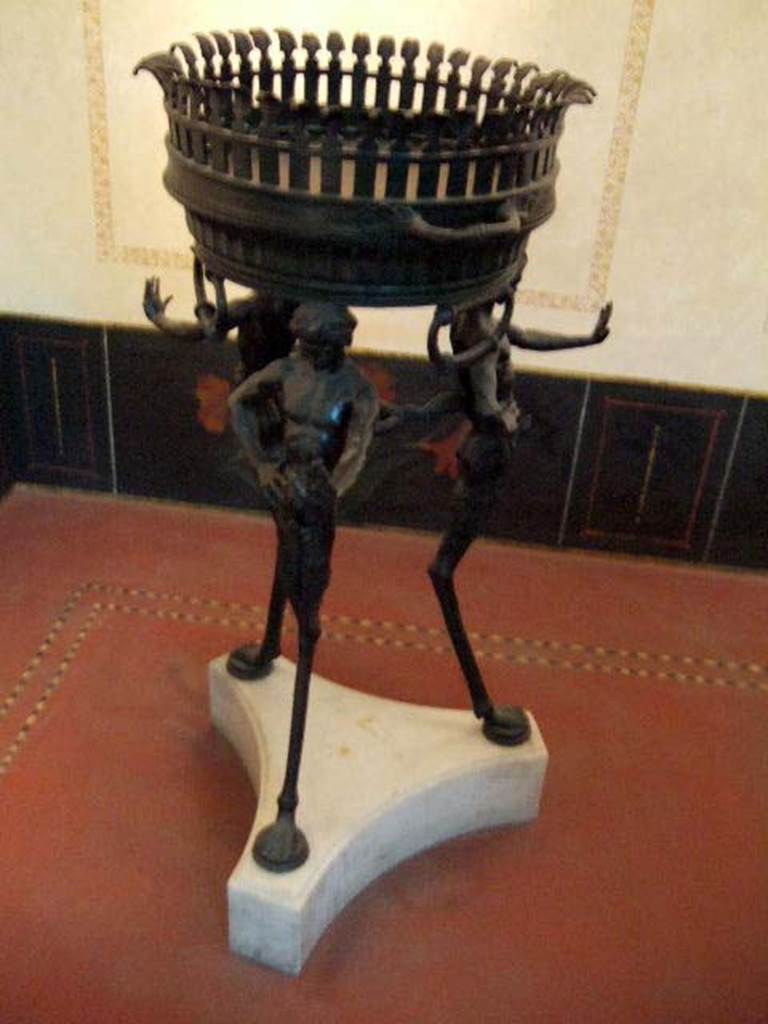 II.4.6 Pompeii. Found 15th June 1755,
Bronze brazier tripod supported by ithyphallic satyrs as legs, found in the sacrarium.  
Now in Naples Archaeological Museum.  Inventory number 27874.
