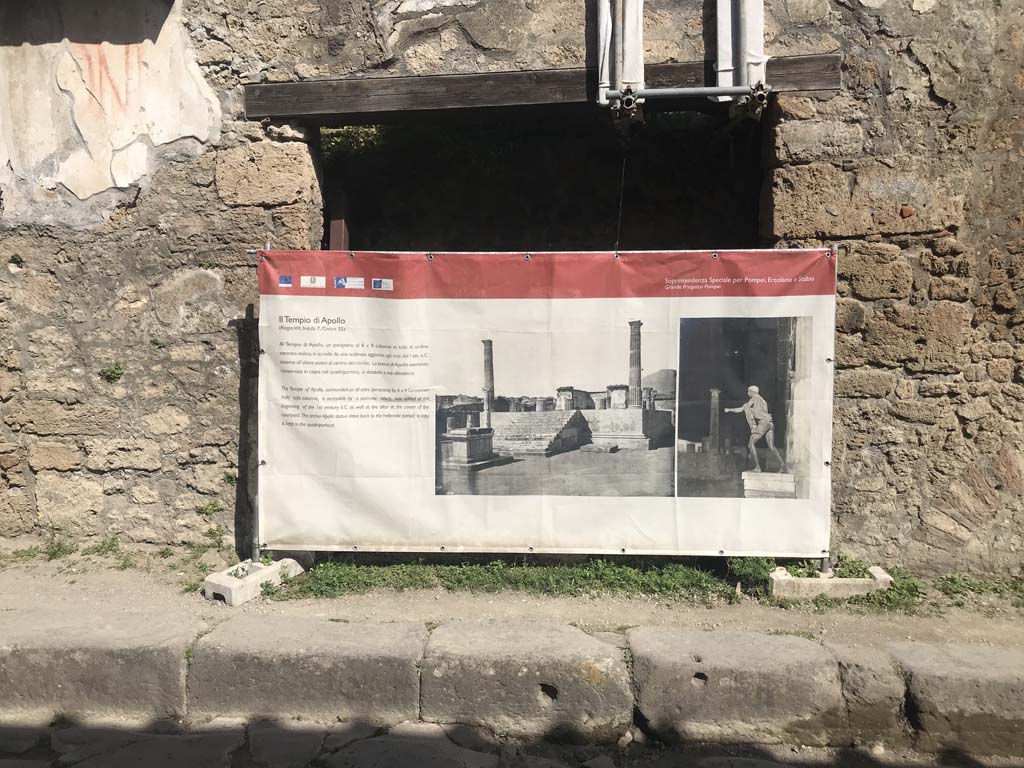 III.2.2 Pompeii. April 2019. Looking towards entrance to shop on north side of Via dellAbbondanza.
The display board, advertising the Temple of Apollo, is a temporary screen.
The Temple of Apollo is to be found in Reg.VII.7.32, on the west side of the Forum.
Photo courtesy of Rick Bauer.
