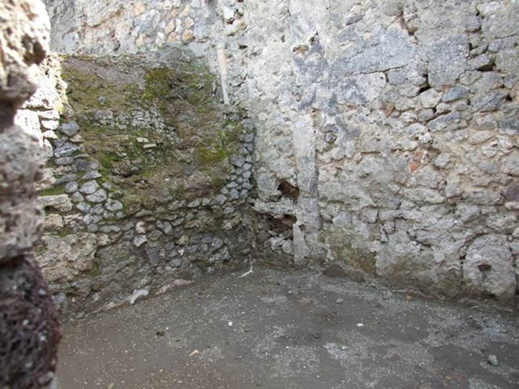 V.1.15 Pompeii. April 2009. Looking south-east through doorway to room on west side of oven, on the south side of the bakery. The side of the large oven can be seen on the left side of the photo.
