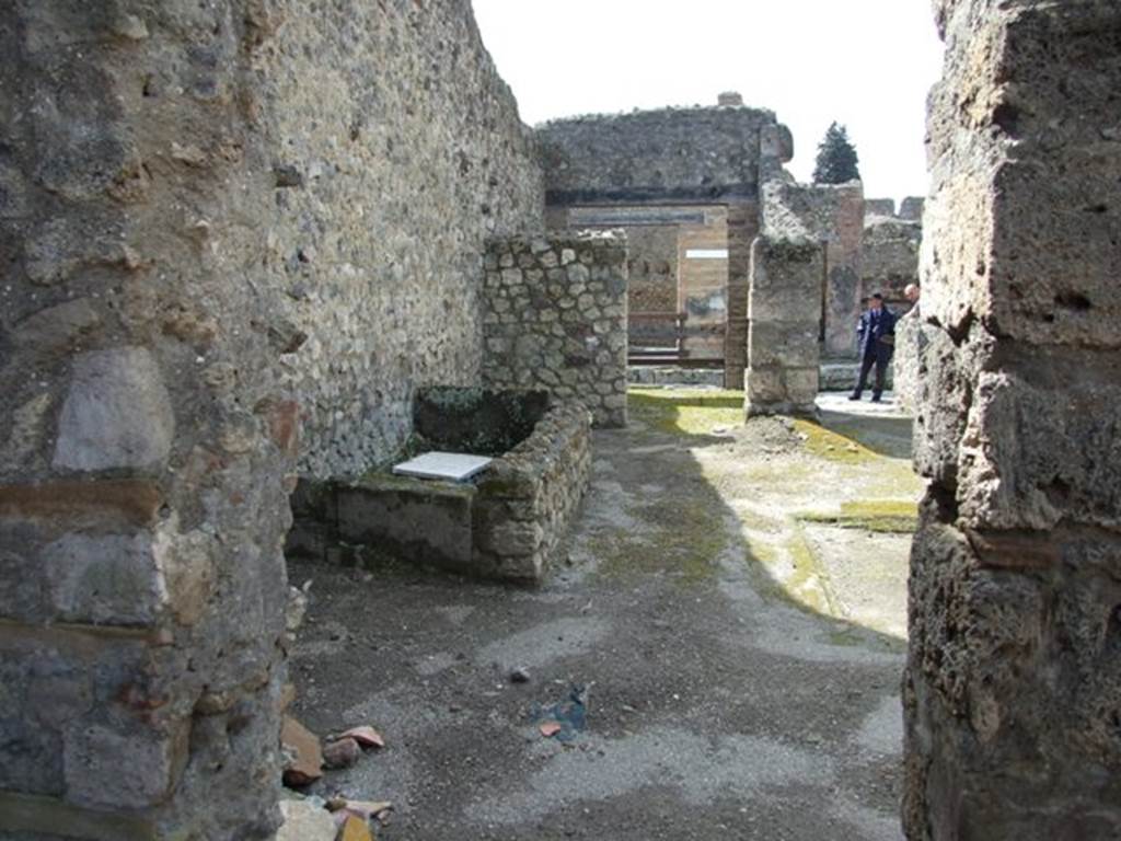 V.1.15 Pompeii.  April 2009. Doorway in west wall from Room on south side of Bakery. Looking west into atrium with water basin against south wall.
