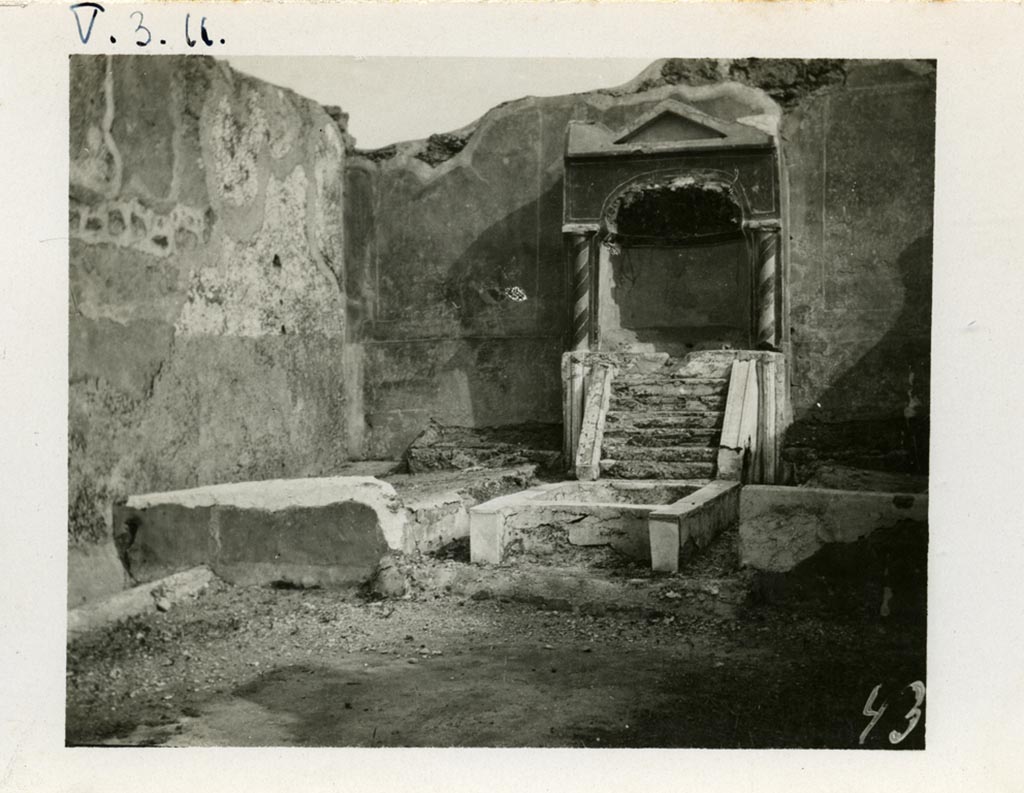 V.3.11 Pompeii. pre-1937-1939. Looking towards south wall of the garden with aedicula fountain niche, pool and biclinium. 
Photo courtesy of American Academy in Rome, Photographic Archive. Warsher collection no. 437.
According to Jashemski –
On the south wall of the small garden (excavated in 1902), there was an aedicula-shaped fountain niche with a masonry couch on either side 
(l. imus and l. summus, 3.00m). There was a crudely painted garden painting above each couch.
Water, perhaps from a statuette carried away in antiquity which stood in the aedicula, ran down the little steps into the rectangular pool below.
The front of the pool was concave, parallel to the curve of the niche; the back of the pool in front of the water-steps was shaped in the same way. 
A jet rose in the centre of the pool. There was a planted area on each side of the pool. 
A mask, intended for use as a fountain, was found in a room off the atrium.
Jashemski sources –
Parabeni, N.Sc, (1902), p.276, 371, 372 (the plan opposite p.369 gives the location of the pipes that carried water to the two fountains in the garden);
Thedenat, p.87.
Soprano, p.306, no.27.
Neuerburg, p.122-23, no.24.
Dohl, p.13.
Dwyer, "Oscilla”, p.279, no.83.
See Jashemski, W. F., 1993. The Gardens of Pompeii, Volume II: Appendices. New York: Caratzas. (p.115).
