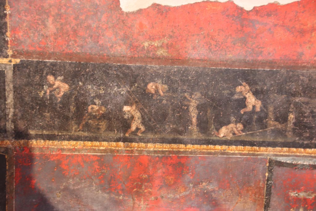 VI.15.1 Pompeii. October 2023. Predella in centre of north wall painted panel of cupids gathering and pressing grapes. Photo courtesy of Klaus Heese.