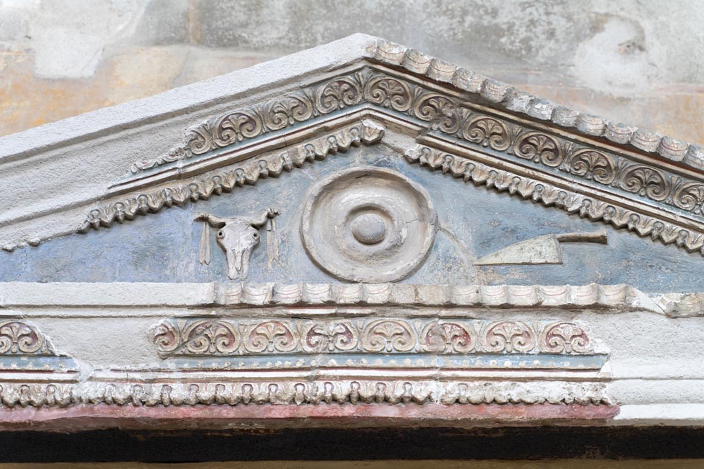 VI.15.1 Pompeii. March 2023. Detail of stucco decoration on aedicula above painted lararium. Photo courtesy of Johannes Eber.