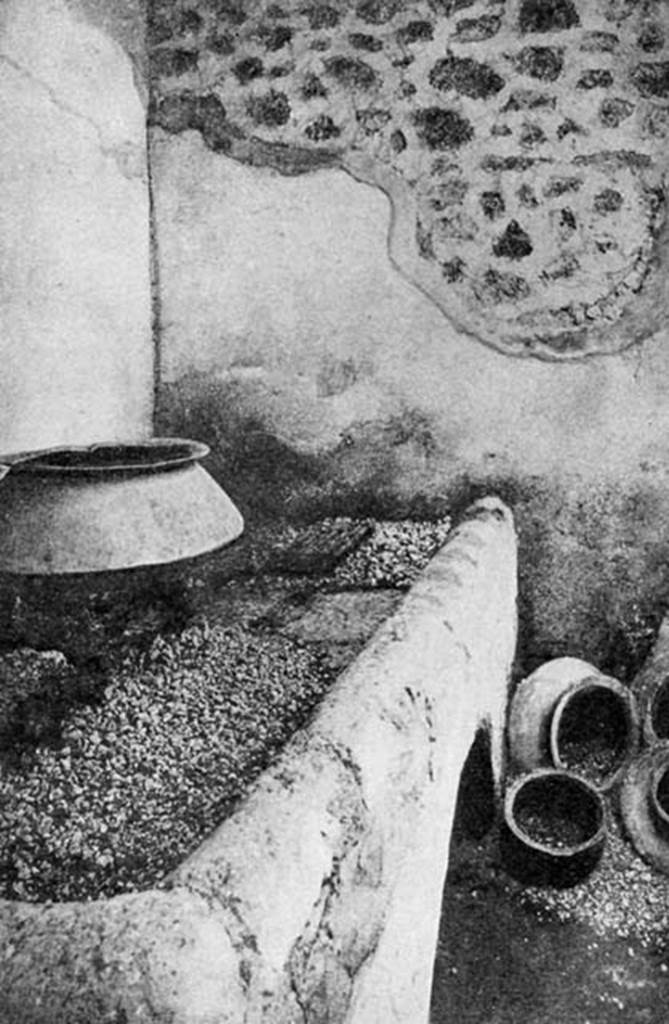 VI.15.1 Pompeii. Undated old photograph. Kitchen oven in service area with pot on tripod on embers and storage pots on floor.