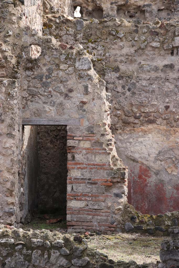 VII.3.8 Pompeii. October 2020. 
Looking south across room “c” towards doorway to latrine “f”, and small cubiculum “d” with red painted plaster.
Photo courtesy of Klaus Heese.

