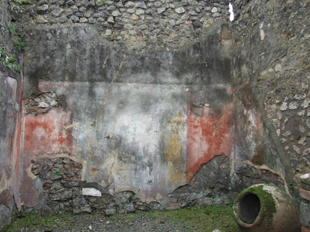 VII.14.5 Pompeii. March 2009. Room 13, south wall with remaining painted plaster. 
The wall would have been painted in the IV Style, with red panels framed by carpet borders and two parallel lines.
The borders would have been separated by architectural decoration which showed, according to Fiorelli, three paintings with fish and landscape. 
No trace of these paintings survives on the south wall.
