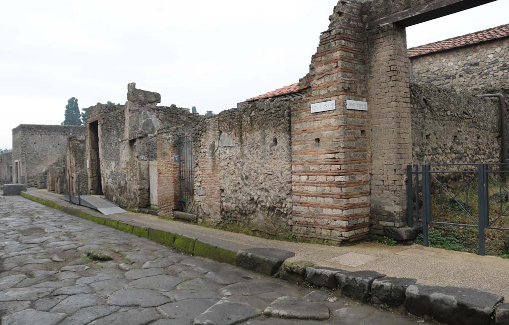 Via dell’ Abbondanza, south side. December 2018. 
Looking east from II.3.1 (and Vicolo della Venere), on right, towards II.3.5 and fountain, on left. Photo courtesy of Aude Durand.
