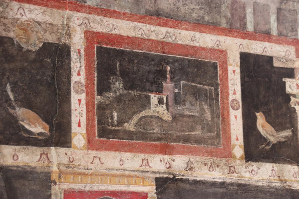 I.9.5 Pompeii. October 2024.
Room 10, triclinium, detail from upper centre of west wall on south side of central painting. Photo courtesy of Klaus Heese.
