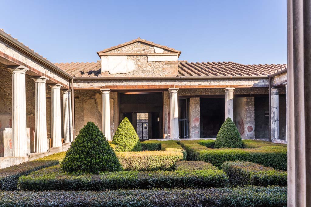 I.10.4 Pompeii. April 2022. 
Looking north across peristyle garden from south-west portico towards tablinum, atrium and entrance doorway.
The doorway to room 11 is behind the columns, in the corner on the left. Photo courtesy of Johannes Eber.


