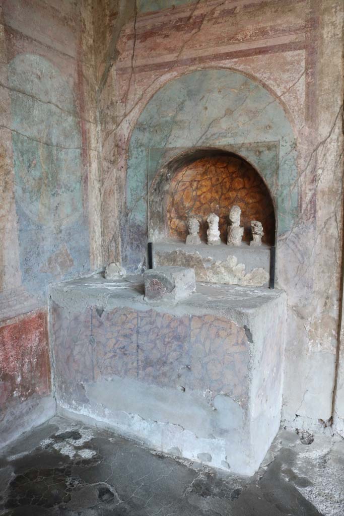 I.10.4 Pompeii. December 2018. 
Alcove 25, altar to household gods against west wall. Photo courtesy of Aude Durand.
The busts are plaster cast taken from the cavities left by the original wooden busts.
These were imagines maiorum, ancestor images, and were accompanied a statuette of a sitting youth, identified as a lar (protective household god).

