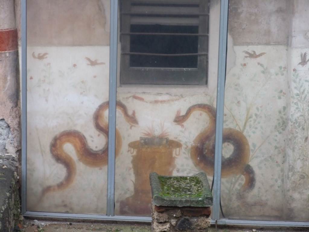 I.11.15 Pompeii. December 2007. Room 10. Garden area with altar and painted Lararium. The Lararium painting has two large diagonal snakes, one either side of a painted round altar. Above the snakes is a garland. In the background are bushes with green leaves and red flowers. Over each bush is a fluttering bird. In front of the painted altar is a four sided real altar which was painted with red, blue and yellow spots. See Fröhlich, T., 1991, Lararien und Fassadenbilder in den Vesuvstädten. Mainz: von Zabern. (L20: p.258 and tafel 3,2).