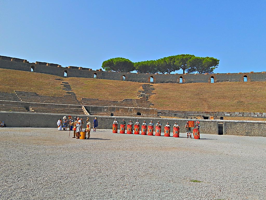 II.6 Pompeii. September 2024. 
Looking west across amphitheatre towards site of preview/rehearsal for a larger event, including Gladiators and Roman Soldiers. 
Photo courtesy of Giuseppe Ciaramella.
