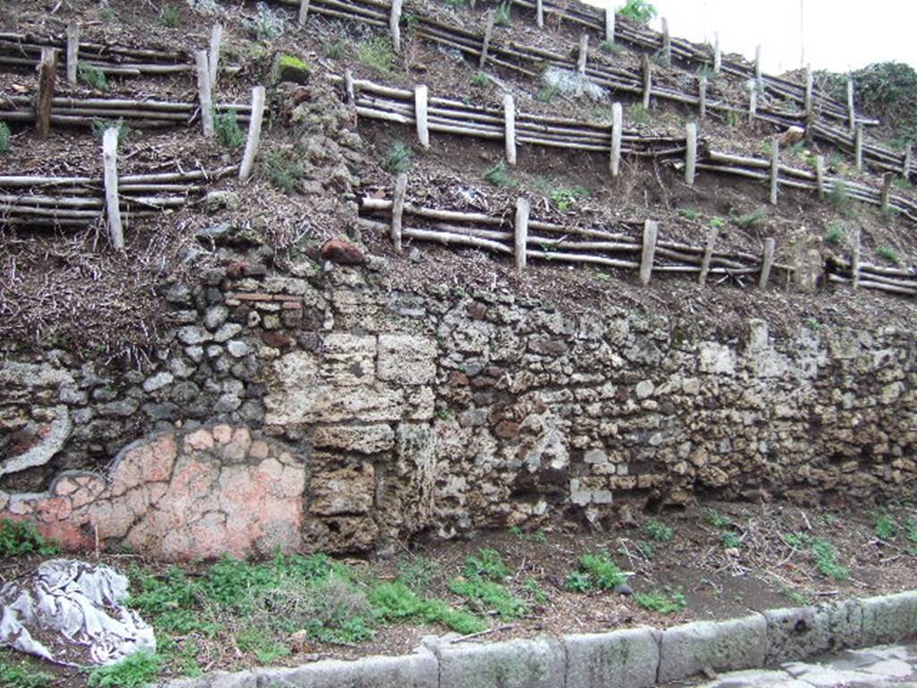 V.6.8, (on left with remaining pink plaster) and V.6.7, Pompeii (on right). December 2005. 
Unexcavated façade on east side of roadway.
