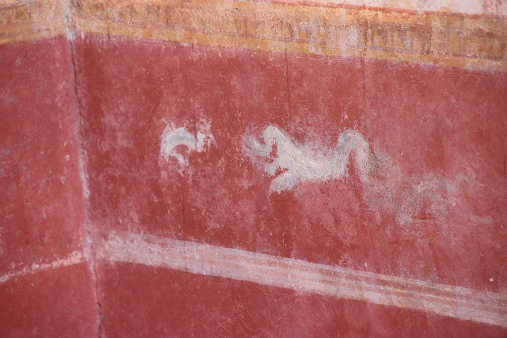 V.6.12 Pompeii. October 2024. Cubiculum 9, painted dolphin and sea creature in zoccolo/dado at east end of south wall. Photo courtesy of Klaus Heese.