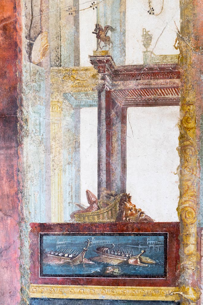 VI.15.1 Pompeii. March 2023. 
North wall of exedra, painted panel of naval scene, with basket and mask above.
Photo courtesy of Johannes Eber.
