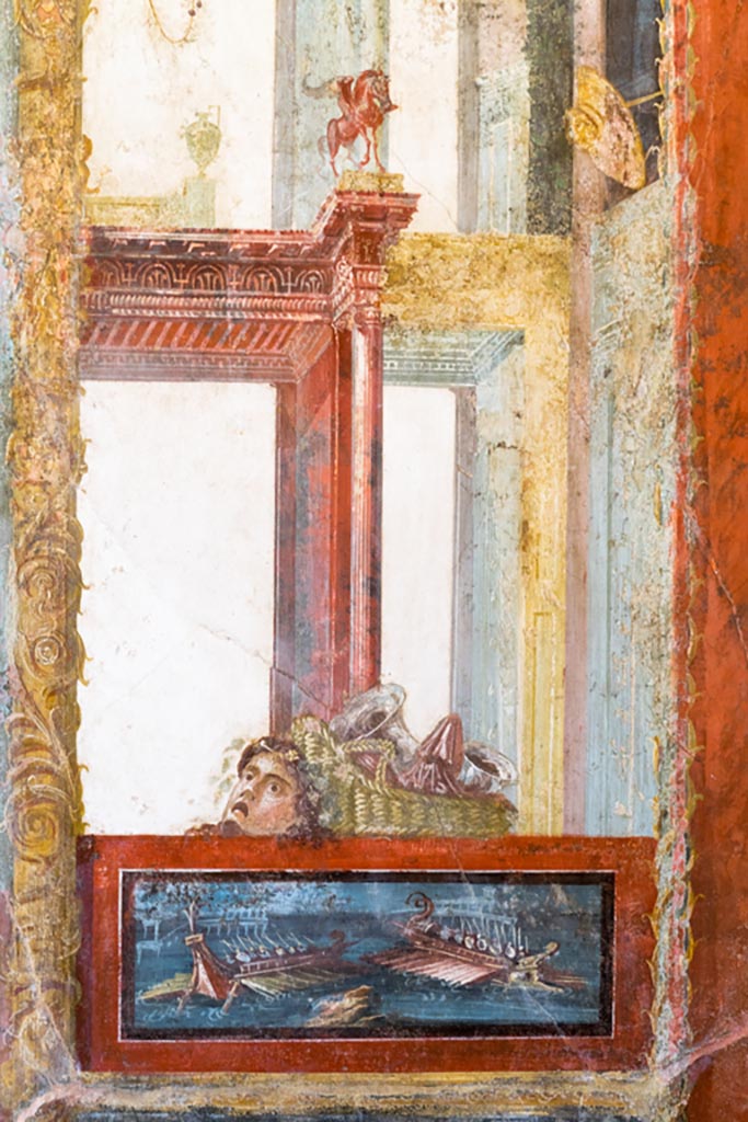 VI.15.1 Pompeii. March 2023. 
North wall of exedra, from east side of central painting, panel with naval scene with mask and basket above.
Photo courtesy of Johannes Eber.

