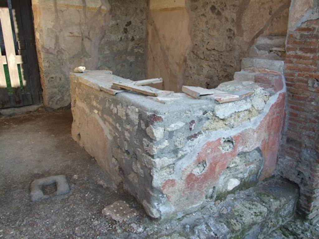 VI.16.32 Pompeii. December 2007. Looking east through entrance VI.16.33 into bar room C. Two-sided counter next to south wall, with painted plaster with red background. The floor was Opus signinum, buried in the floor near the entrance from the street was a piece of lava-stone with a hole in the middle for the closure bar. The walls have a high brick dado, and above this was a simple white plaster. The dado was divided into panels by vertical yellow bands. In the centre of each panel was a painting of a feeding bird, except that on the right of the entrance doorway to the atrium, which showed two birds (See VI.16.33). At the rear in the east wall can be seen the doorway into the atrium B.
