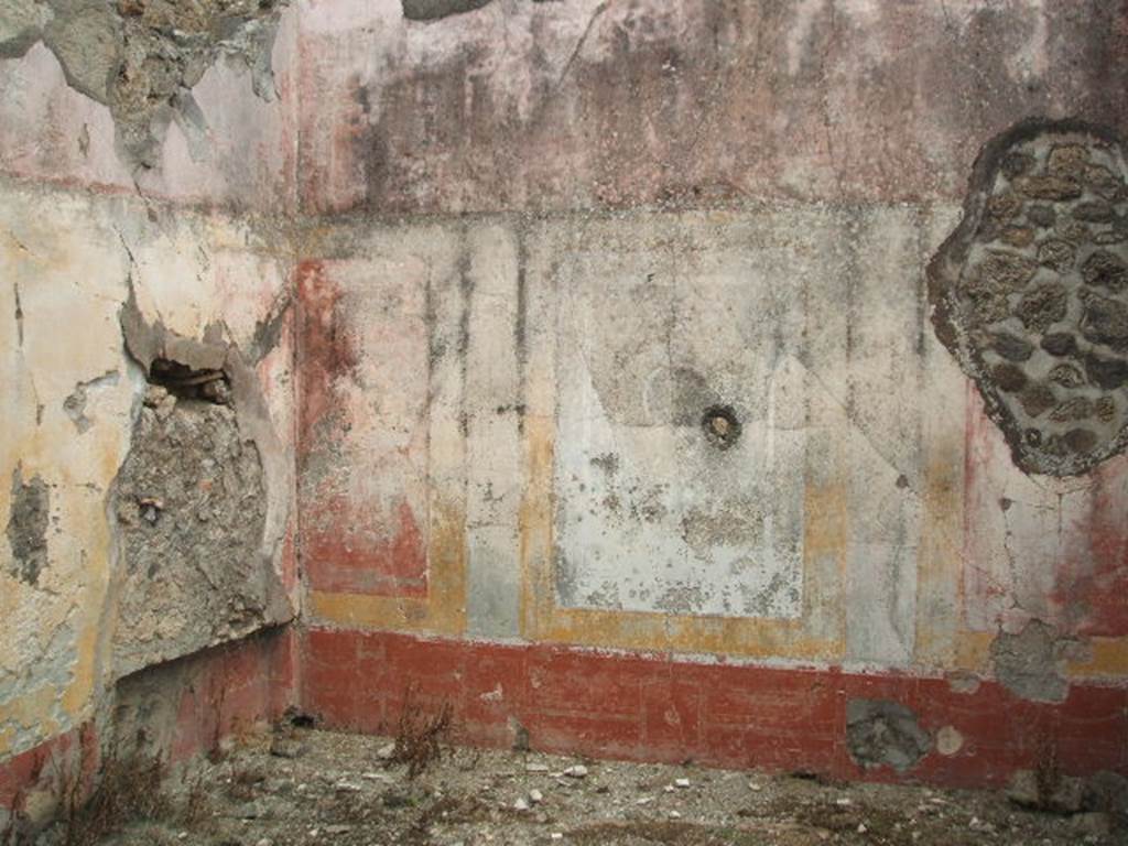 IX.5.18 Pompeii. May 2005. Room o, oecus in north-east corner, a spacious room, decorated with red, yellow and white, in the centre of which were two rounds showing groups of Cupid with Psyche.
See NdS 1878, (p.269)
In the north wall, on left, the recess for the couch can be seen. The zoccolo was red, separated by compartments with painted animals. In the white centre of the middle zone was a medallion (now faded), in which was seen the group of Eros with a rod and Psyche holding a peacock between her arms. The upper zone of the wall was white with painted architectural details.
