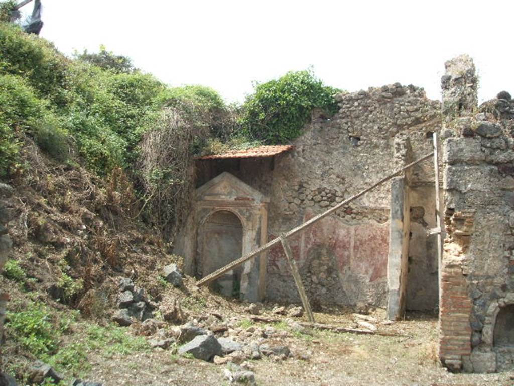 IX.6.8 Pompeii. May 2005. Looking towards west wall of garden area 9 with large aedicula lararium in south-west corner. In the north-west corner is a partition wall forming a cupboard/storeroom. The garden, entered directly from the atrium, occupied the south-west part of this small house. In the south-west corner of the garden stood a large aedicula niche lararium.  The interior of the niche, coated with yellow stucco, had a painting of a leafy tree with birds flying around it.  On the floor of the niche was a rectangular, stucco covered base, which Sogliano identified as an altar. Boyce identified it as a statue base decorated with a painted mask on the front.
See Jashemski, W. F., 1993. The Gardens of Pompeii, Volume II: Appendices. New York: Caratzas. (p.238)
According to Boyce, his reference was Not.Scavi, 1880, 231; Bull. Inst., 1882, 116.
See Boyce G. K., 1937. Corpus of the Lararia of Pompeii. Rome: MAAR 14. (p.87, no.432, and Pl.37,1) 
According to Giacobello, aedicula on west wall of garden, today not conserved. It was of rectangular form opening into an arched niche decorated with a stucco shell. On the lower part, frescoed in yellow, were birds in flight, and a cherub with a double flute near to the depicted tree. Recovered from inside the niche, was an altar decorated with marble, and on the main side, was a tragic mask. 
See Giacobello, F., 2008. Larari Pompeiani: Iconografia e culto dei Lari in ambito domestico.  Milano: LED Edizioni. (p.286)
