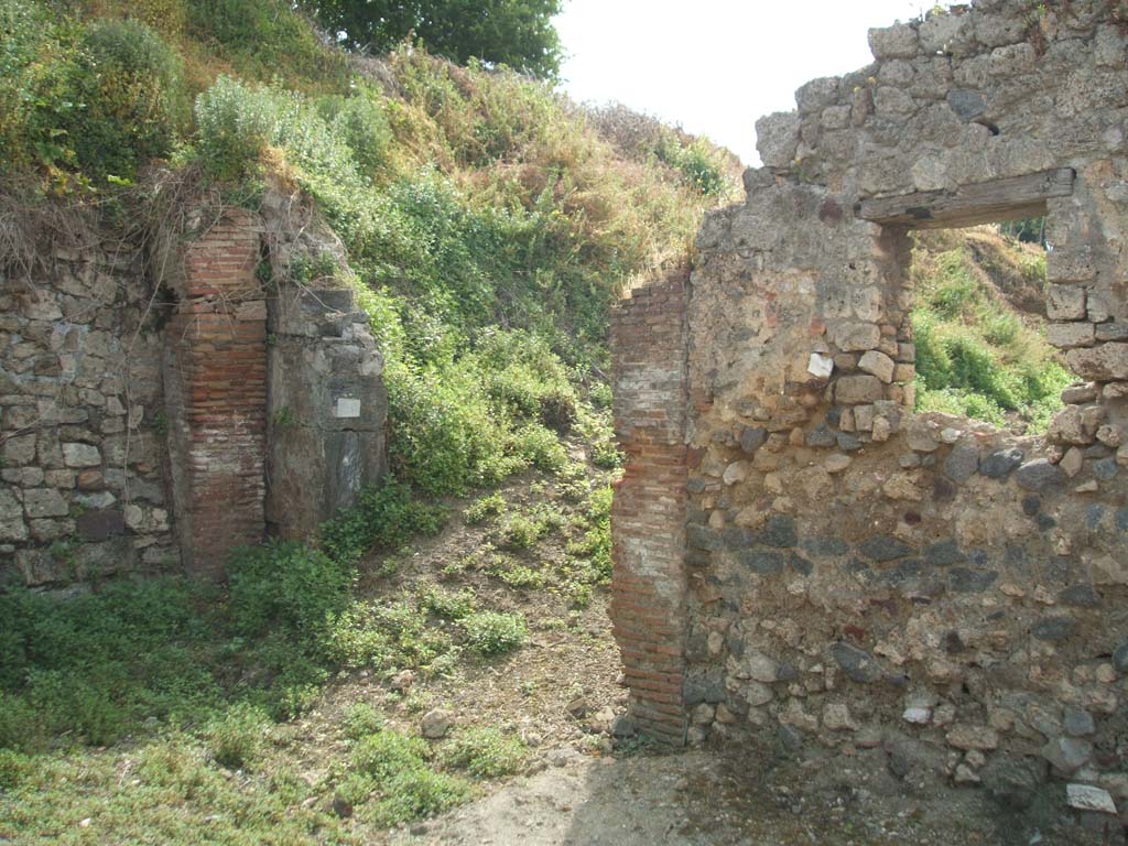 IX.7.26 Pompeii. May 2005. Looking south from end of small roadway towards entrance and room (d).
According to Della Corte, this hostelry had an annexed room for its clients. 
He also deduced from the electoral recommendation written in the middle of the external wall between IX.7.26 and 25, the names of the two Pompeians that managed these two premises - 
Fabius Memor cum (Fabio) Celere rogat     [CIL IV 3841, although DC showed it as 3481)
See Della Corte, M., 1965. Case ed Abitanti di Pompei. Napoli: Fausto Fiorentino. (p.197)

According to Epigraphik-Datenbank Clauss/Slaby (See www.manfredclauss.de),  it read -

Herennium
Celsum  aed(ilem)  o(ro)  v(os)  f(aciatis)
Fabius  Memor  cum  Celere         [CIL IV 3841]
