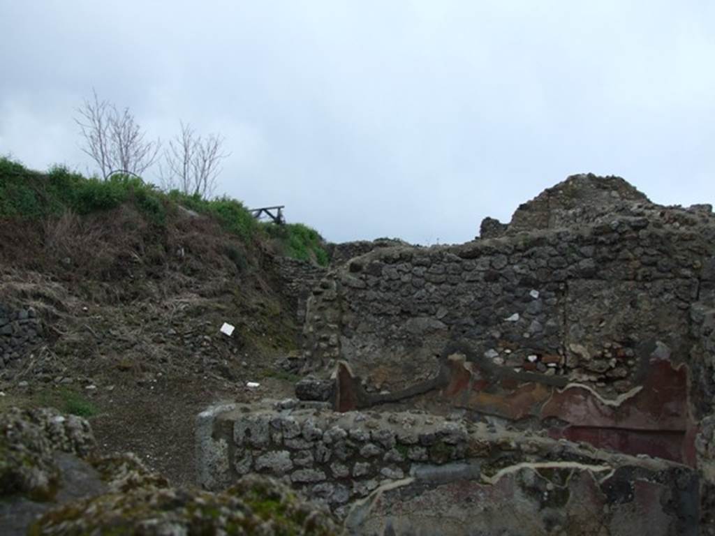 IX.8.c Pompeii. March 2009.  Looking south-west from IX.8.6 across exedra to west wall of small room or cupboard. The unexcavated can be seen on the south side of the peristyle.
