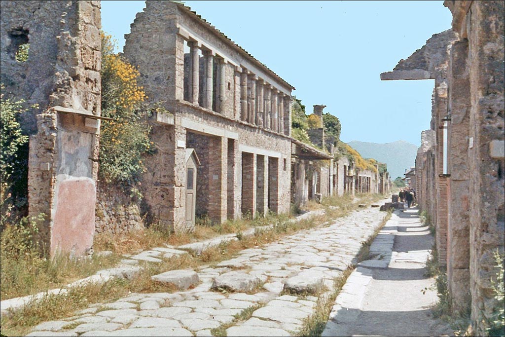 IX.11.8 Pompeii, on left, with graffiti. June 1962. Looking east between IX.12 and 1.8 on Via dell’Abbondanza. 
Photo by Brian Philp: Pictorial Colour Slides, forwarded by Peter Woods
(P43.14 POMPEII House facades along a principal street)
