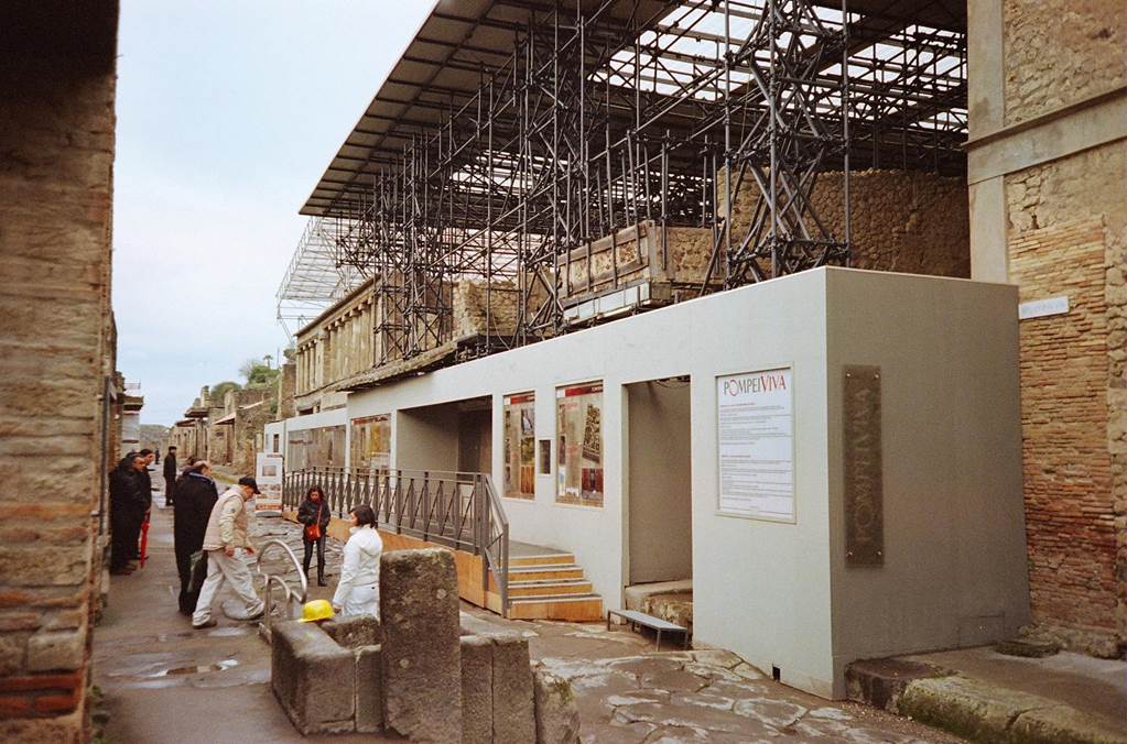 IX.12.7 Pompeii. February 2010. Via dell’Abbondanza looking west, with balcony remains above the PompeiViva frontage. Photo courtesy of Rick Bauer.