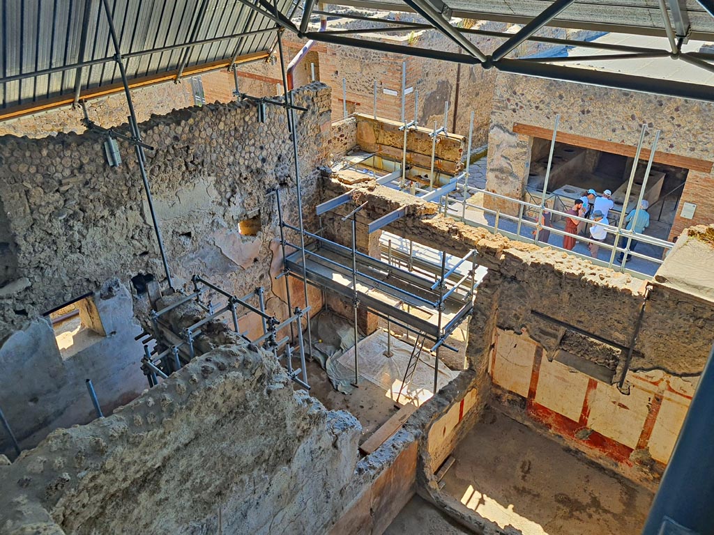 IX.12.7 Pompeii, on left. June 2024. 
Looking south-east towards doorway in shop-room 1 onto Via dell’Abbondanza, in centre, and room “c” of IX.12.6 in lower right. 
The rear room 2 has a window in the east wall onto the side vicolo, on left.  Photo courtesy of Giuseppe Ciaramella.
.
