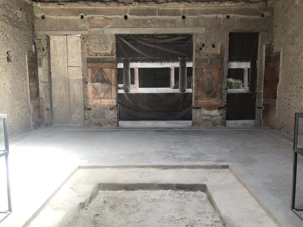 Villa of Mysteries, Pompeii. April 2019. 
Room 64. Looking east across atrium towards blinds with photo of peristyle A imprinted on it, across two of the entrance doorways.
On either side of the impluvium is a display case containing a “body” plaster-cast.
Photo courtesy of Rick Bauer.

