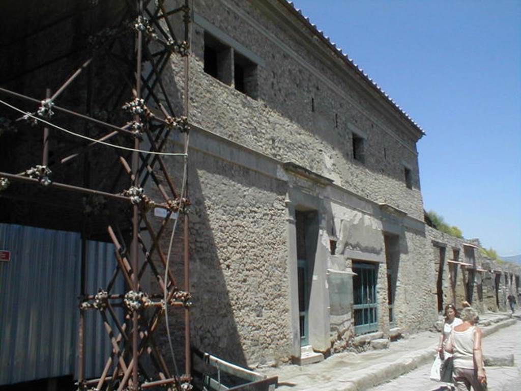 Via dell’Abbondanza, north side. September 2004. Looking east from junction with unnamed vicolo (behind blue metal fencing) on left, towards IX.13. 

