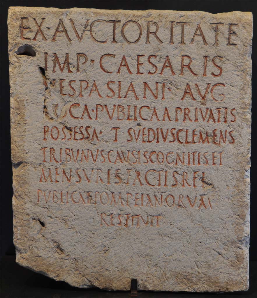 HGW05 Pompeii. Cippus of Suedius Clemens. Found 16th August 1763.
Found on the south of the street close to the entrance to HGW05, almost opposite to the circular seat of Mamia.
Now in Naples Archaeological Museum. Inventory number 3848.
Photo  Livius.org Use subject to  Creative Commons Attribution-ShareAlike 3.0

The inscription reads
EX AVCTORITATE
IMP CAESARIS
VESPASIANI AVG 
LOCA PVBLICA A PRIVATIS
POSSESSA T SVEDIVS CLEMENS
TRIBVNVS CAVSIS COGNITIS ET
MENSVRIS FACTIS REI
PVBLICAE POMPEIANORVM
RESTITVIT      [CIL X 1018]

According to Epigraphik-Datenbank Clauss/Slaby (See www.manfredclauss.de) this reads

Ex auctoritate
Imp(eratoris) Caesaris
Vespasiani Aug(usti)
loca publica a privatis
possessa T(itus) Suedius Clemens
tribunus causis cognitis et
mensuris factis rei
publicae Pompeianorum
restituit      [CIL X 1018]

By virtue of authority conferred upon him by the Emperor Vespasian Caesar Augustus, 
Titus Suedius Clemens, tribune, having investigated the facts and taken measurements,
restored to the citizens of Pompeii public places illegally appropriated by private persons.

Similar Cippi were found at the Porta Marina, Porta Nocera and the Porta Vesuvio.
The wording rei publicae Pompeianorum on this one, discovered in 1763, was the first positive identification that the site was Pompeii. 
Until then scholars had divided opinions on the city buried under Civita. Many, including the first official excavators, thought it was the ancient city of Stabiae.
See Conticello, B., Ed, 1990. Rediscovering Pompeii. Rome: LErma di Bretschneider. (p. 225).
